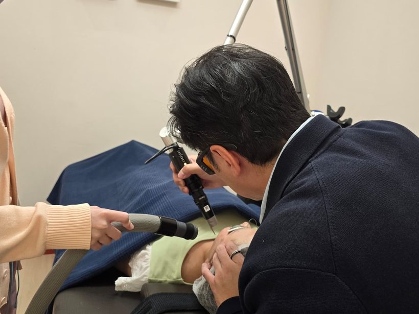 Dr Ong Jin Khang wearing laser safety goggles while performing a pigment laser treatment on a patient in the clinic