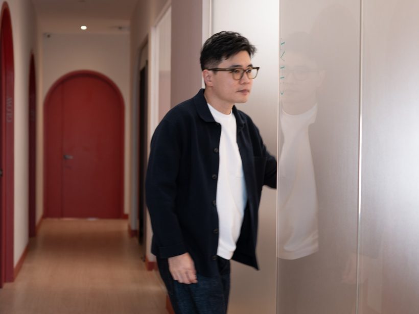 Dr Ong Jin Khang walking alone along a clinic corridor, seen from behind, in contemplative stride
