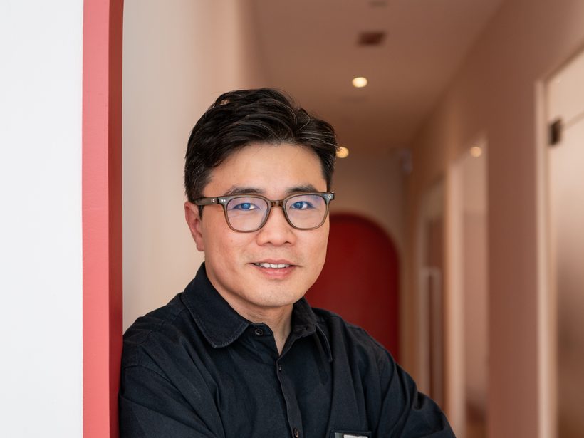 Dr Ong Jin Khang in the clinic corridor, leaning against a doorway in natural light